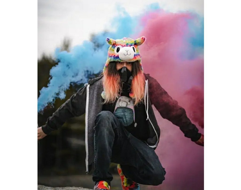 woman wearing a plush toy hat in front of blue and pink smoke